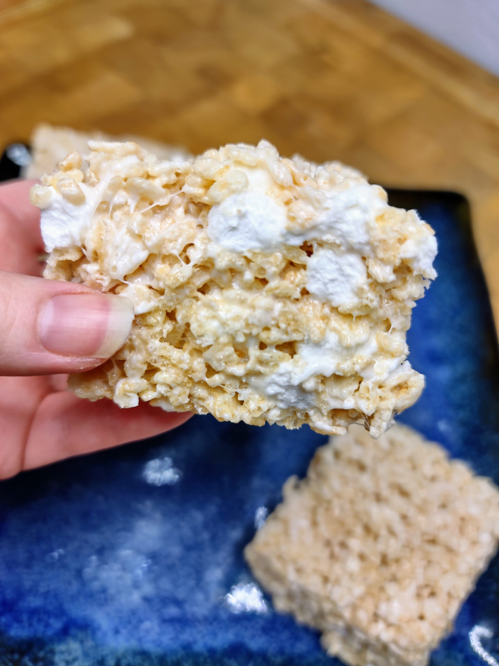 closeup of rice krispie treat being held over a blue plate.