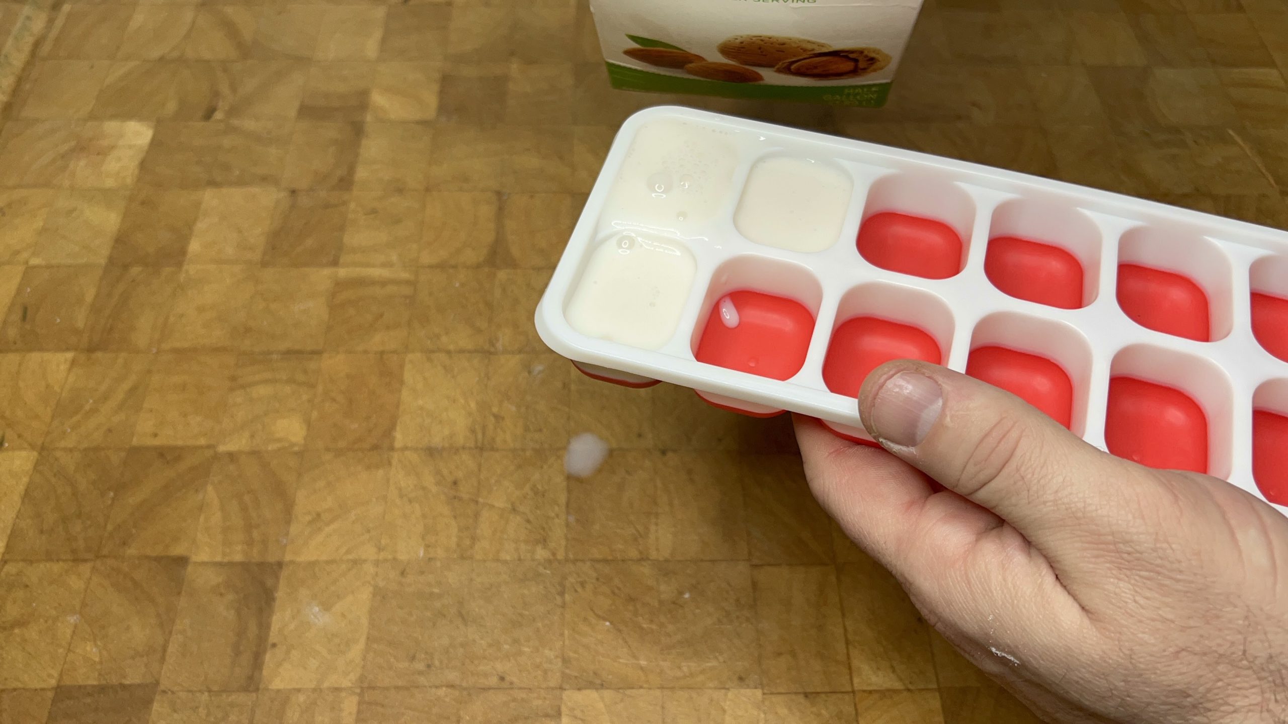 pouring almond milk into ice cube tray