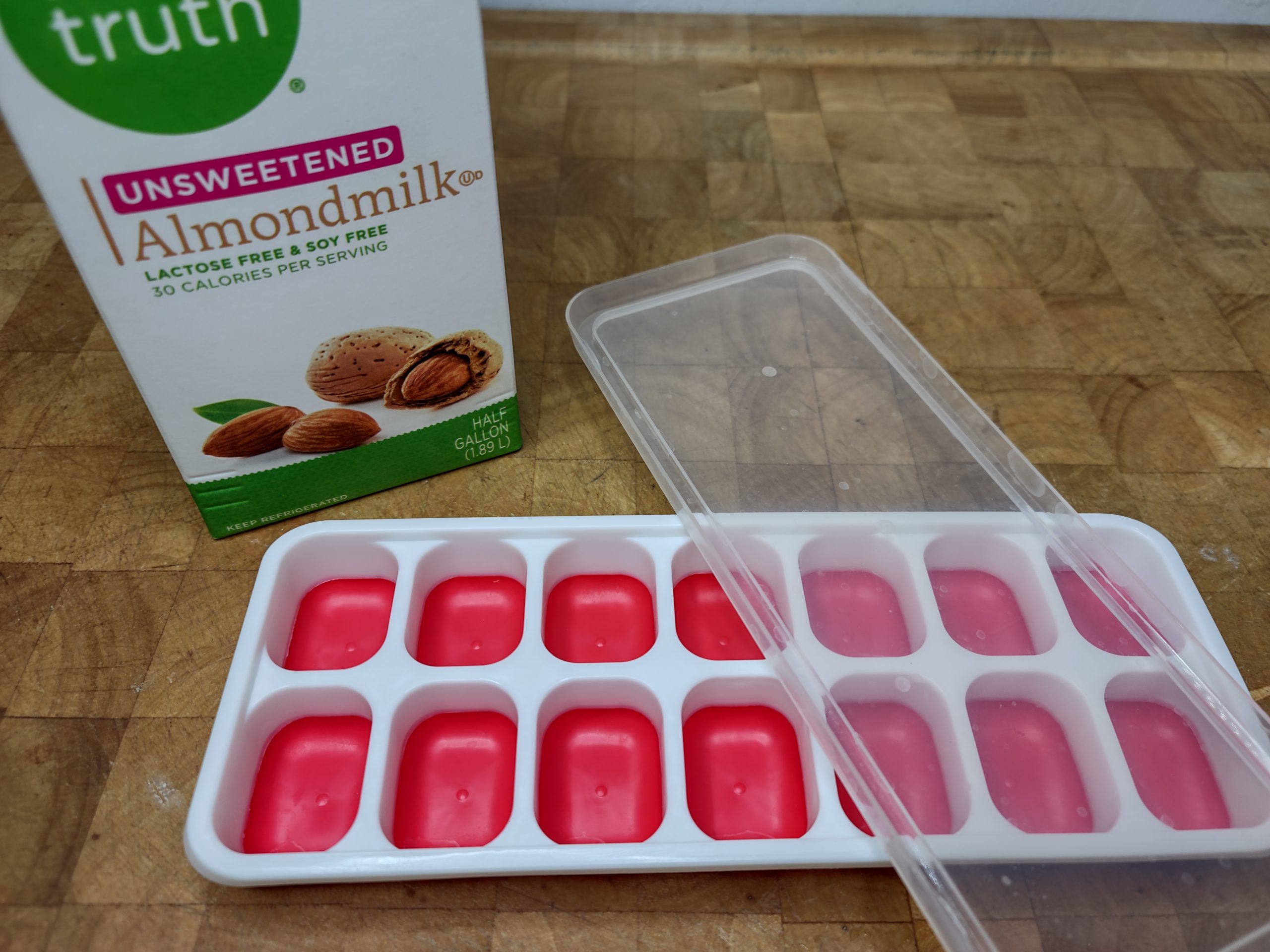 carton of almond milk sitting behind ice cube tray with lid