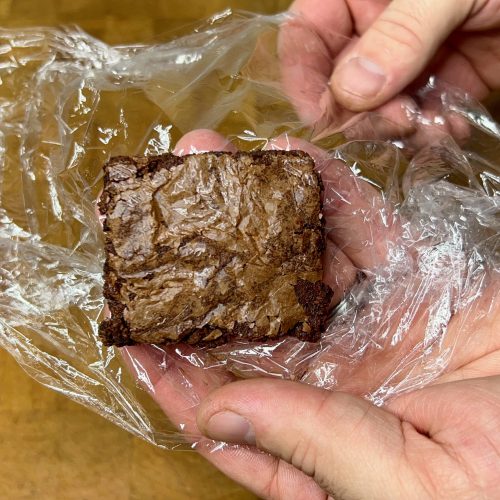 holding brownie sitting on a sheet of plastic wrap