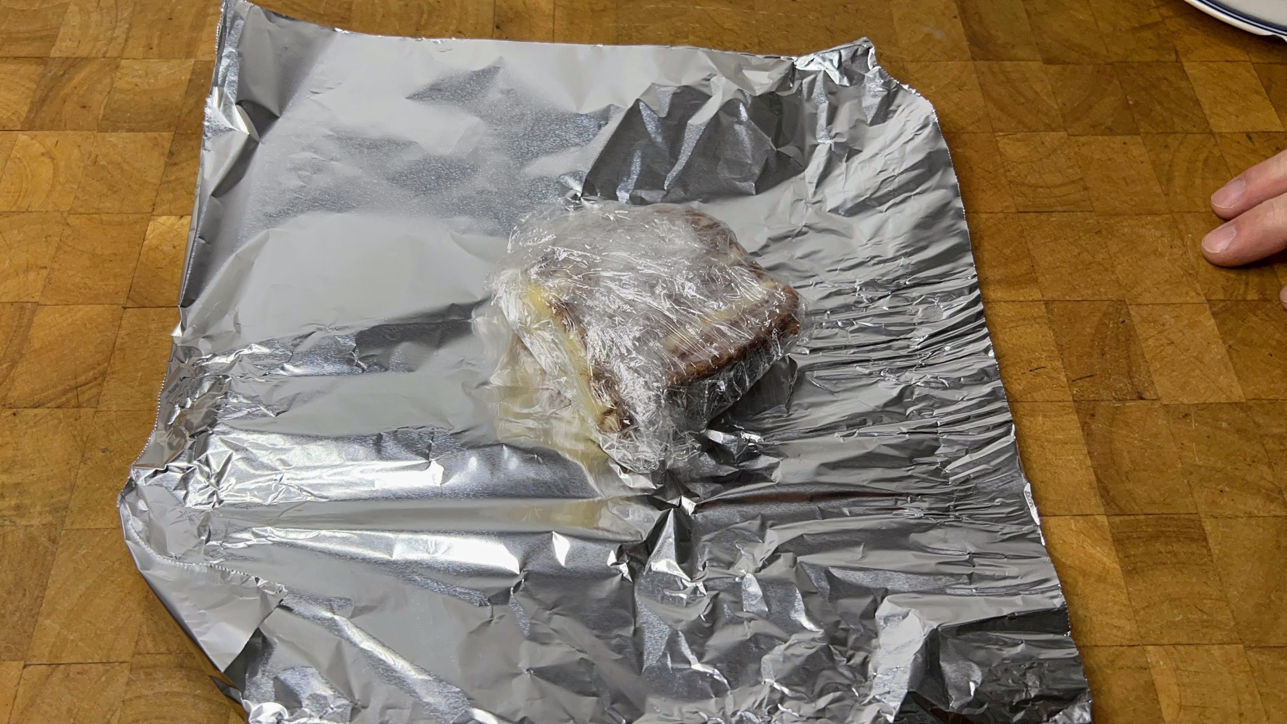 carrot cake wrapped in plastic wrap sitting on a sheet of aluminum foil