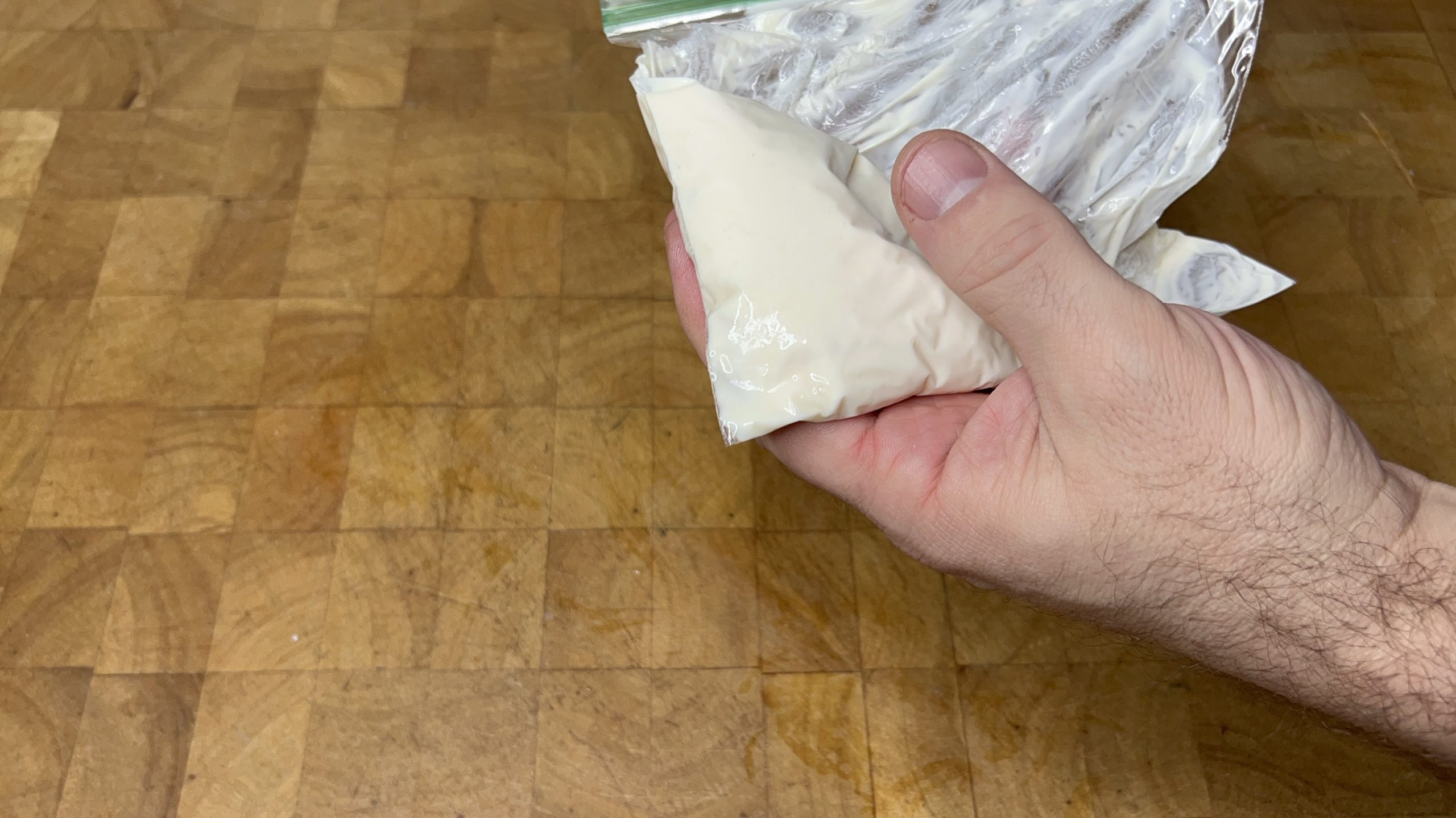 pressing defrosted cream cheese frosting to bottom of freezer bag