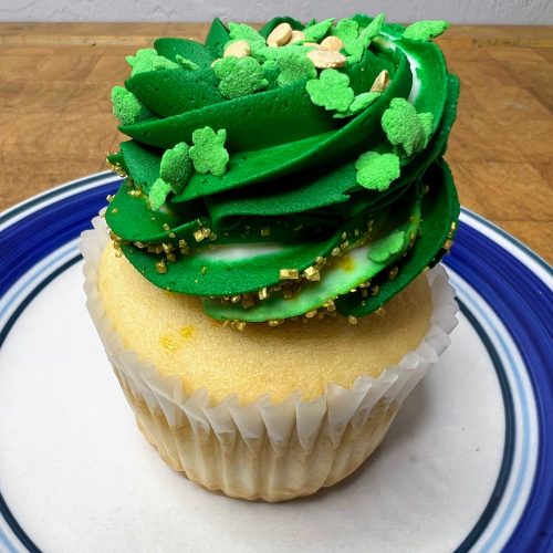 closeup of a cupcake with green shamrock frosting on a blue and white plate