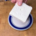 frozen feta cheese being held over a plate