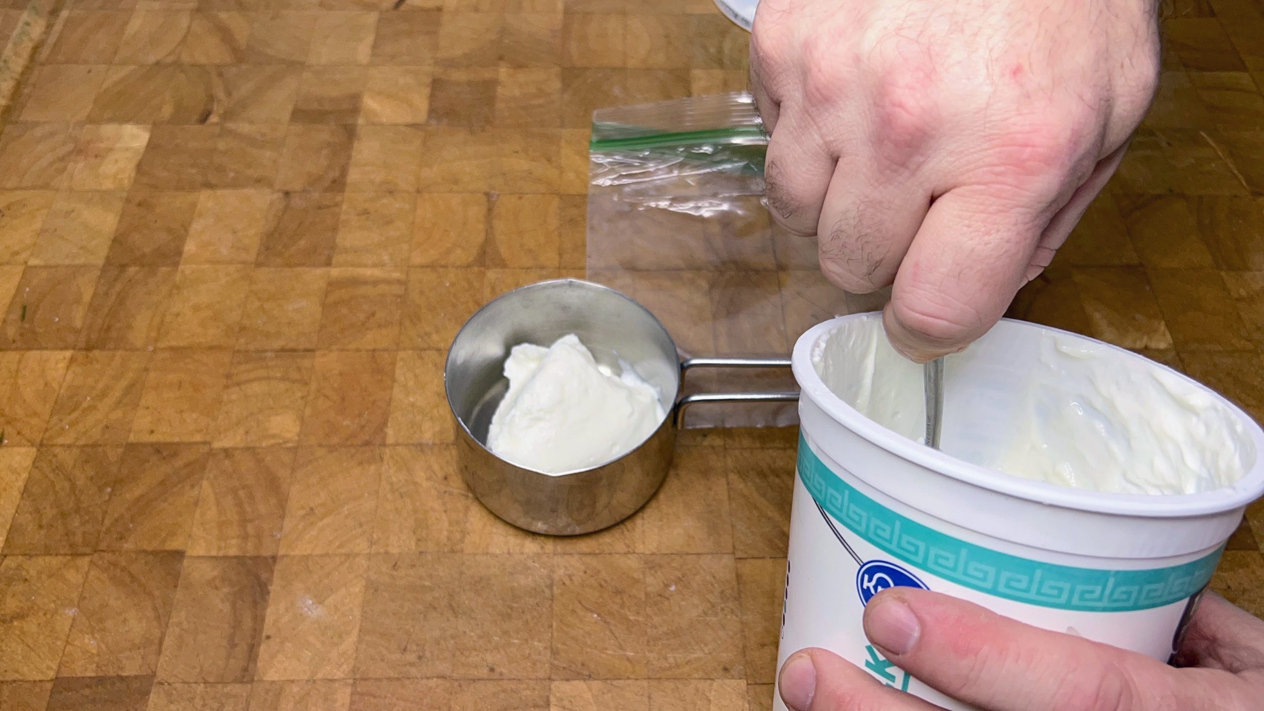 spooning greek yogurt into a measuring cup