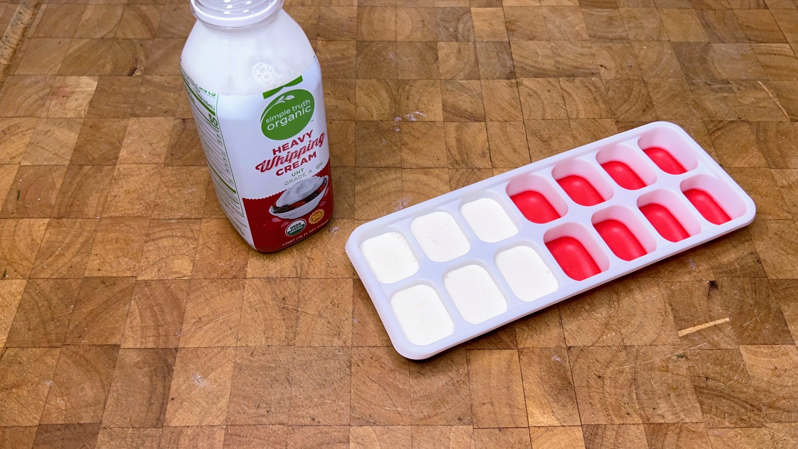 ice cube tray with heavy cream in it and a bottle of heavy cream next to the tray