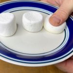 three marshmallows on a plate, pressing on the far right one