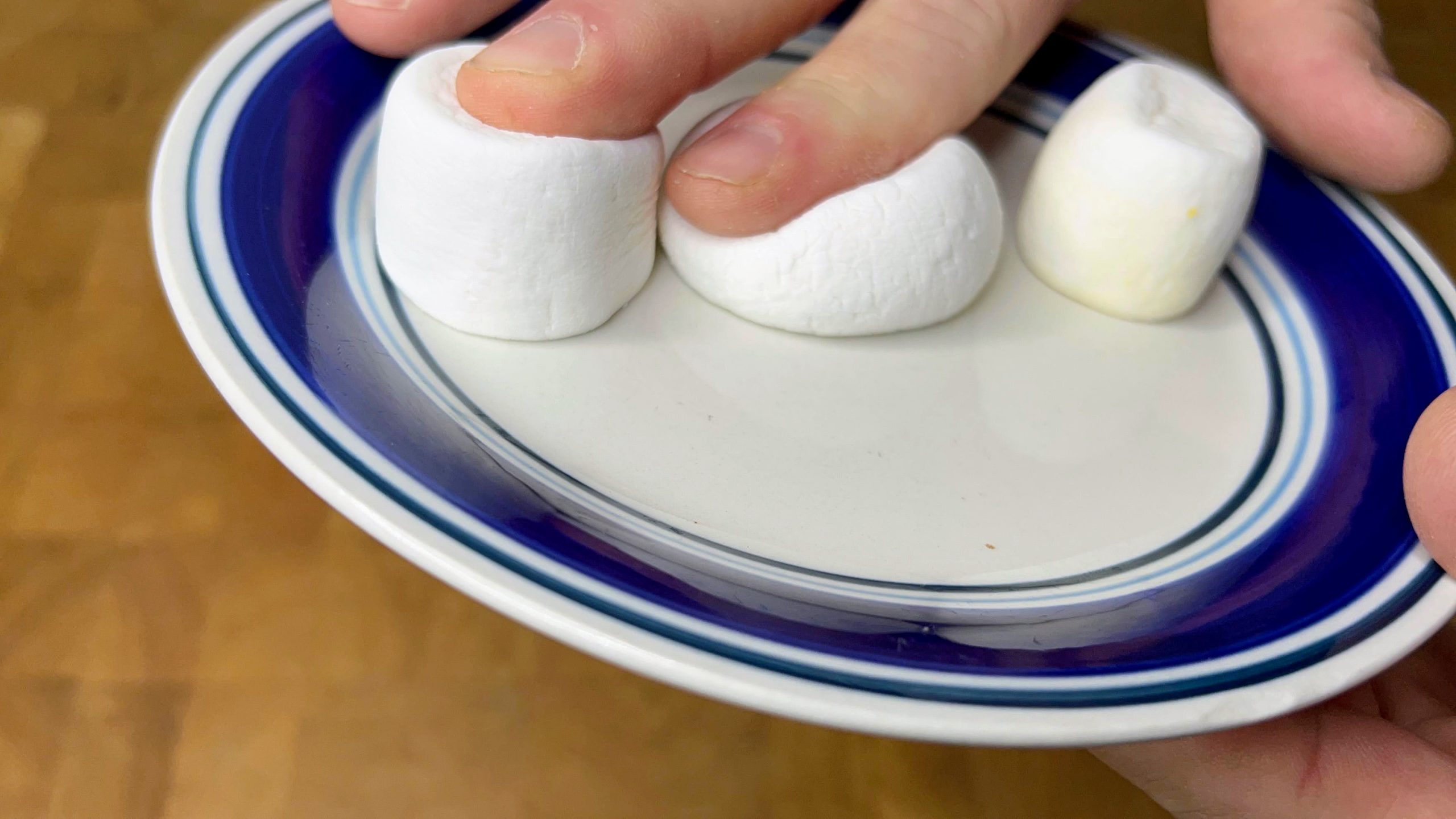 three marshmallows on a plate, pressing on far left and middle one