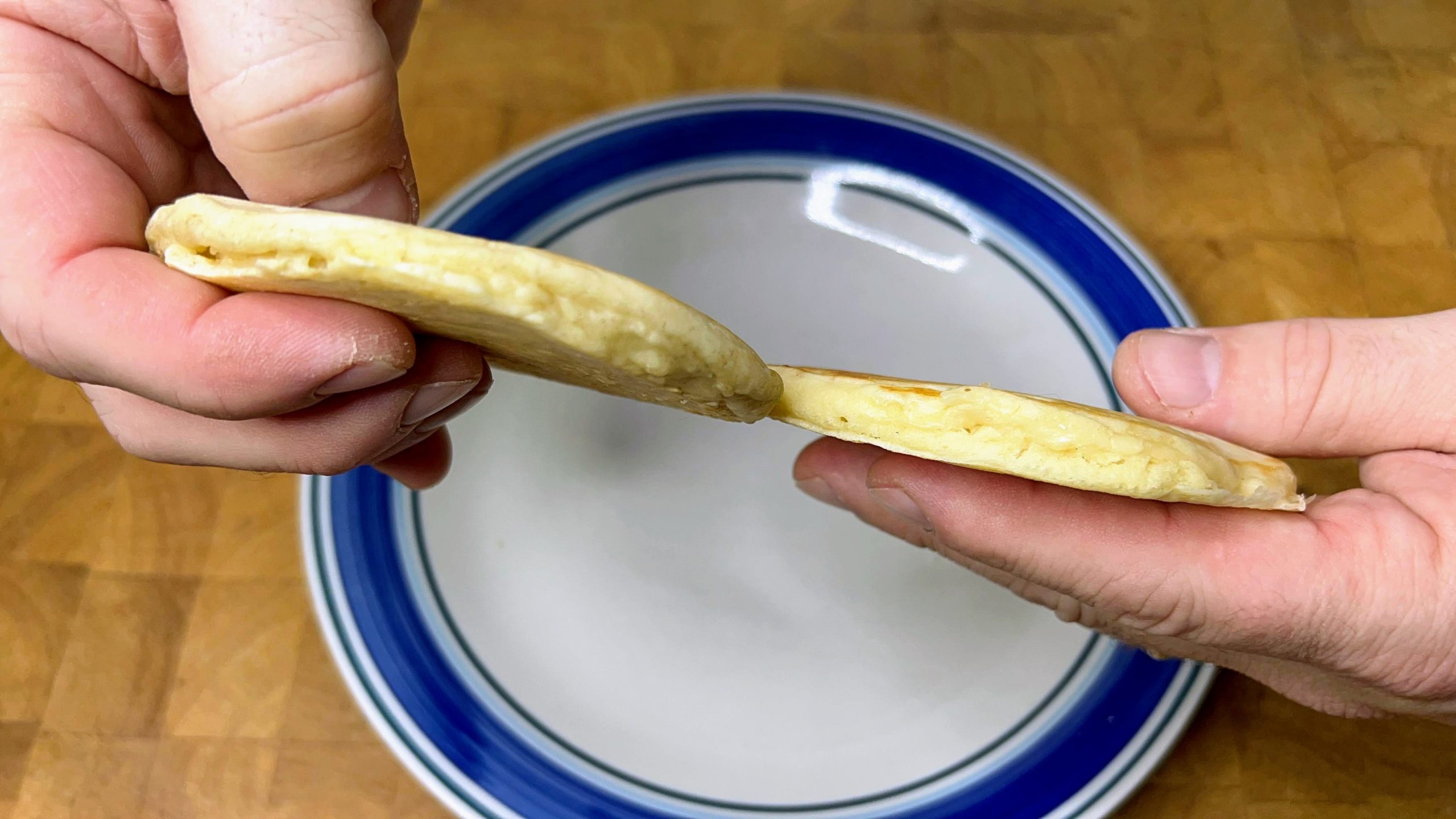 hands holding two pancakes. 
fresh pancake on left, pancake from defrosted batter on right