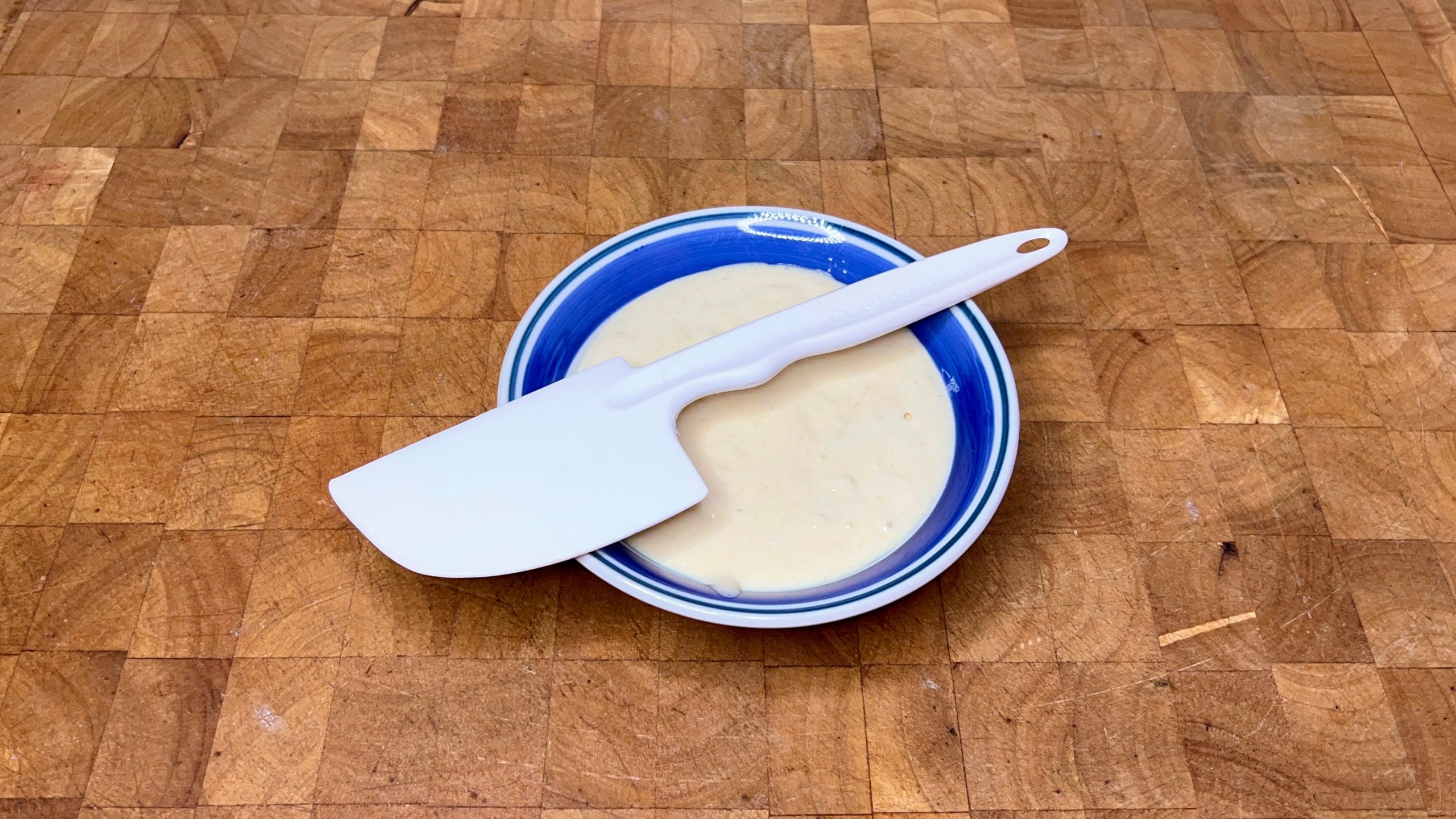 bowl of pancake batter with spatula on top on a wooden table