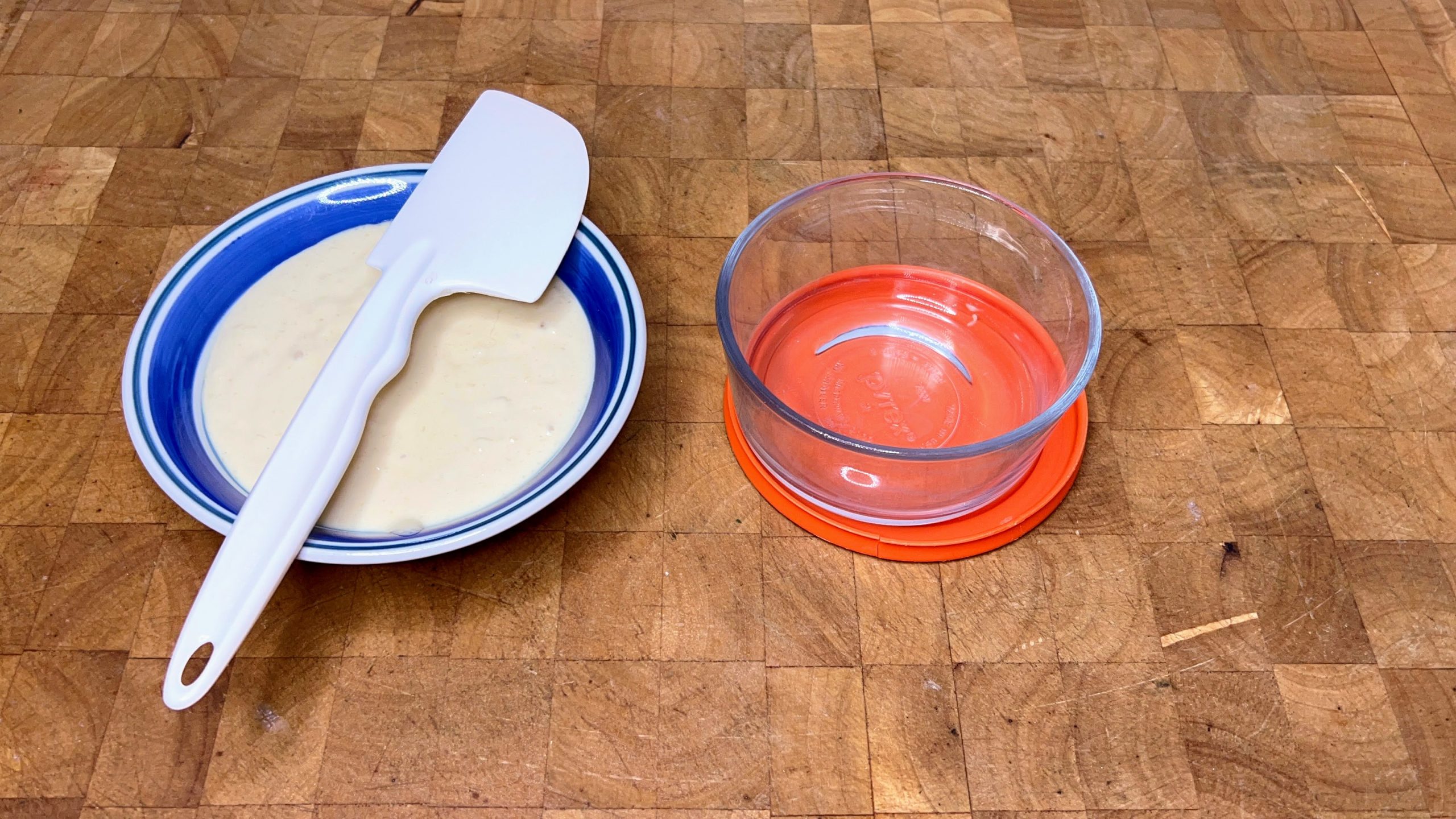 bowl of pancake batter with spatula next to an empty pyrex