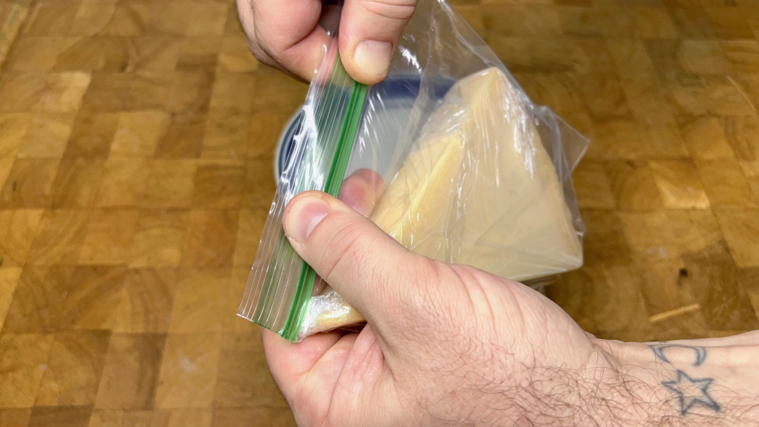 zipping freezer bag full of wrapped parmesan cheese