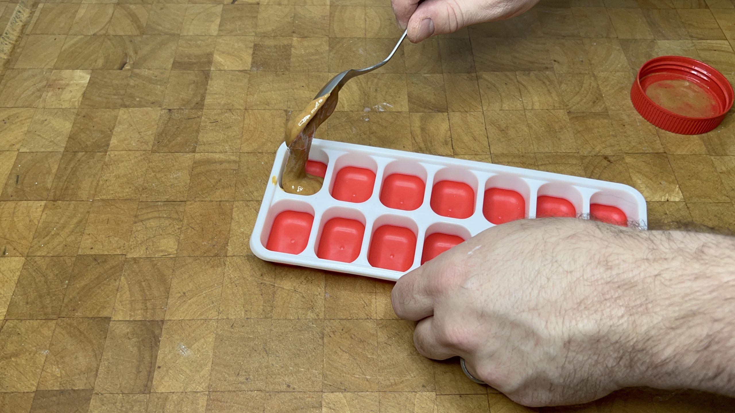 spooning peanut butter into an ice cube tray