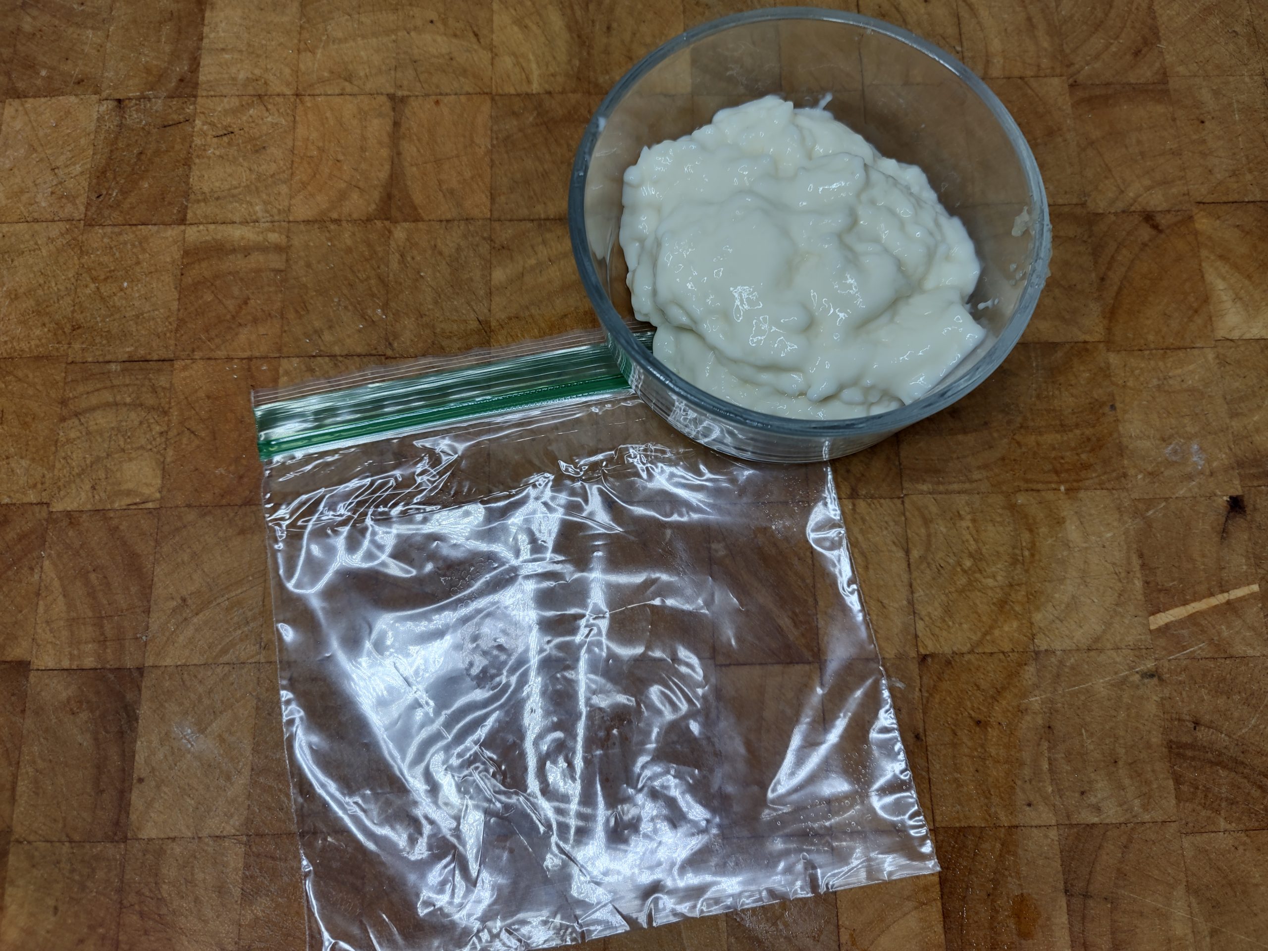 bowl of rice pudding next to an empty freezer bag on a wooden table
