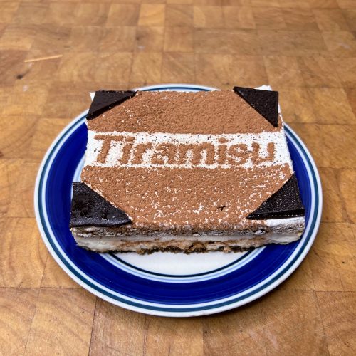 tiramisu on a blue plate on a wooden table