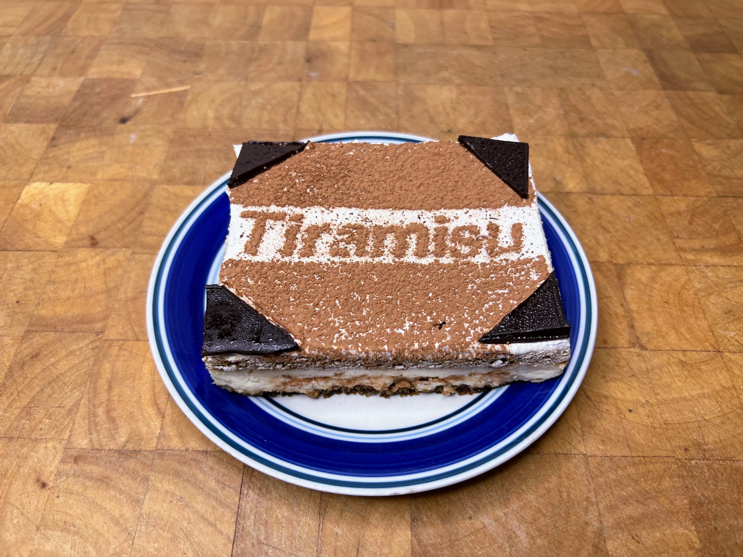 tiramisu on a blue plate on a wooden table