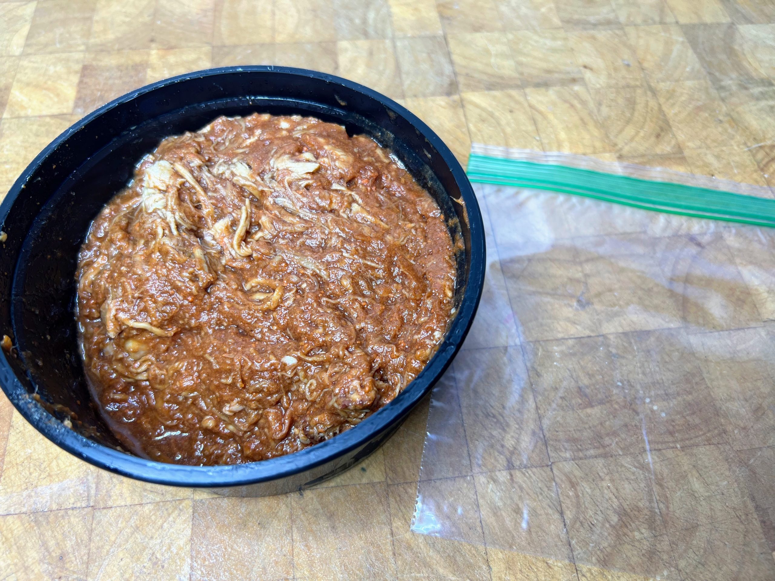 bowl of pulled pork next to an empty freezer bag
