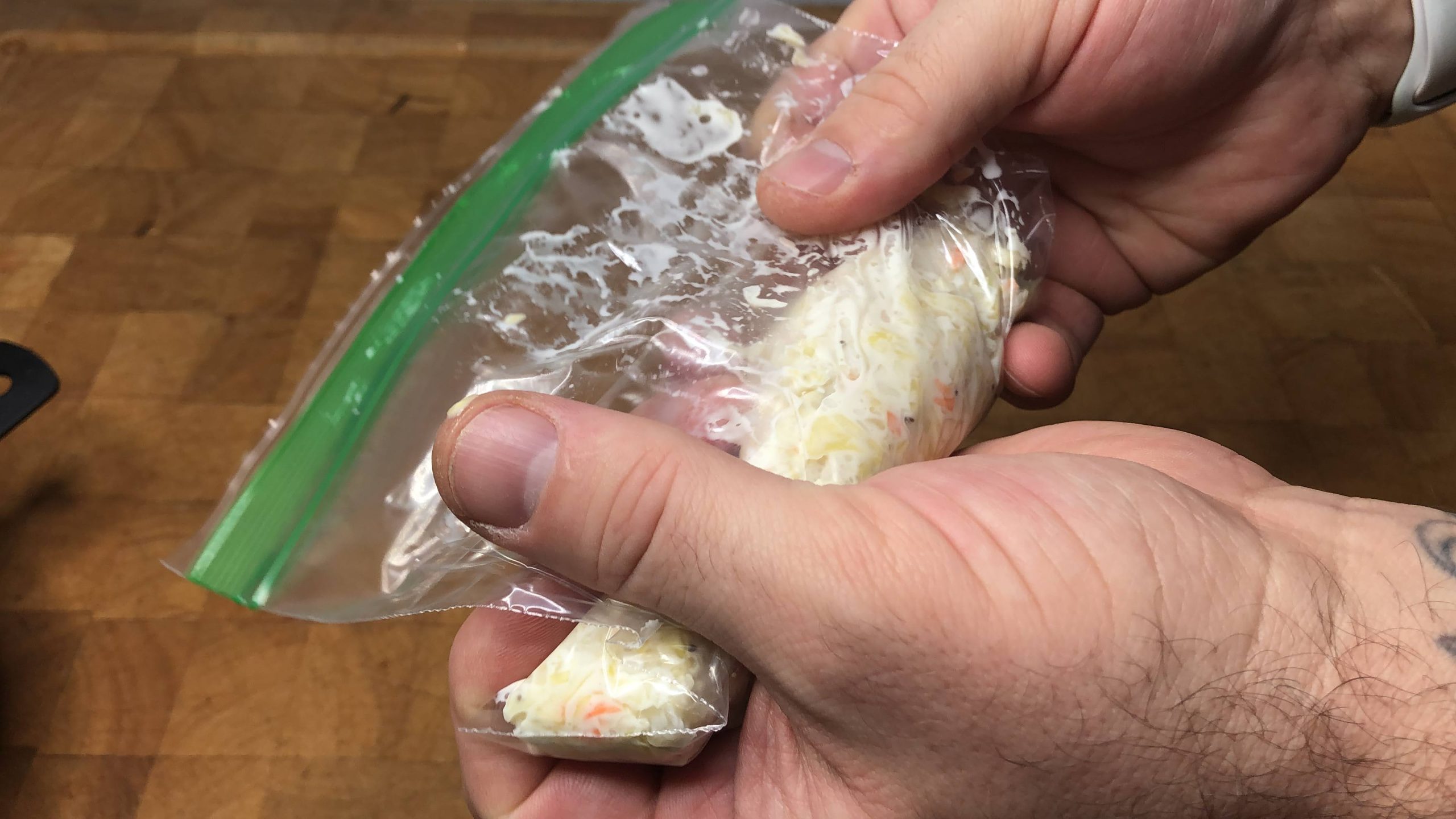 squeezing air out of a freezer bag filled with coleslaw