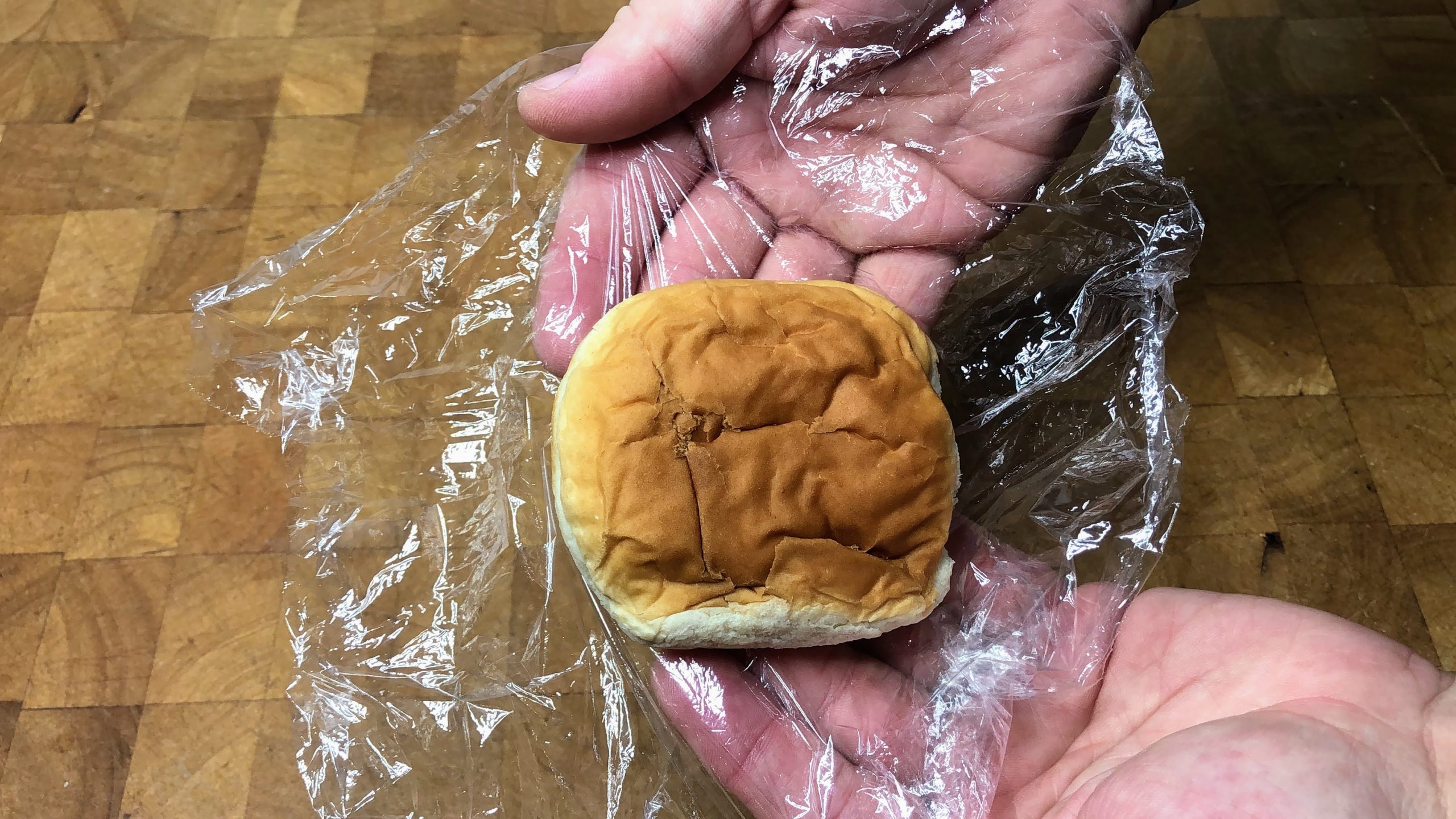 defrosted hamburger bun on a sheet of plastic wrap