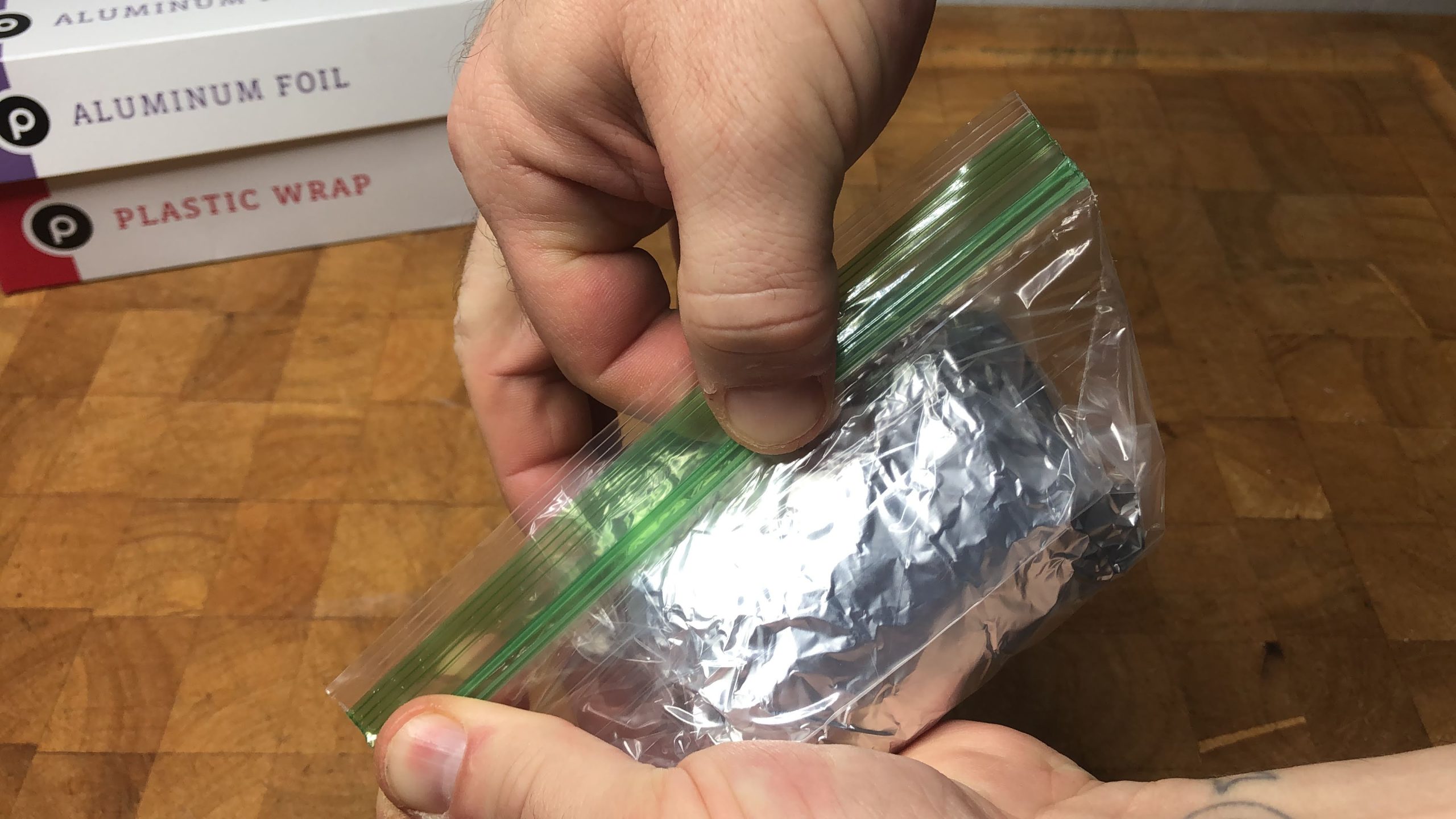 zipping a freezer bag closed that has a aluminum foil wrapped hamburger bun in it