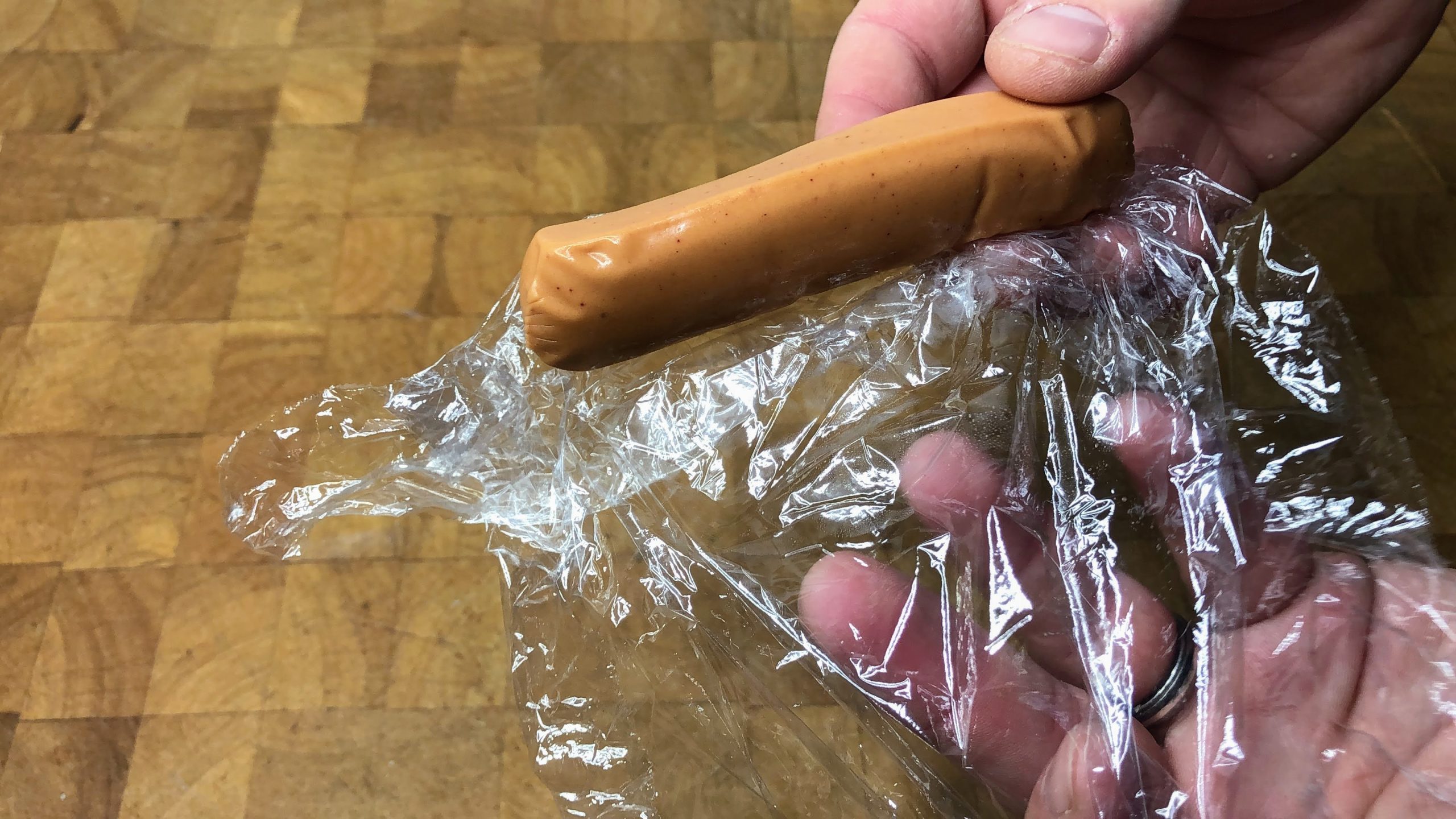 defrosted hot dog on a sheet of plastic wrap
