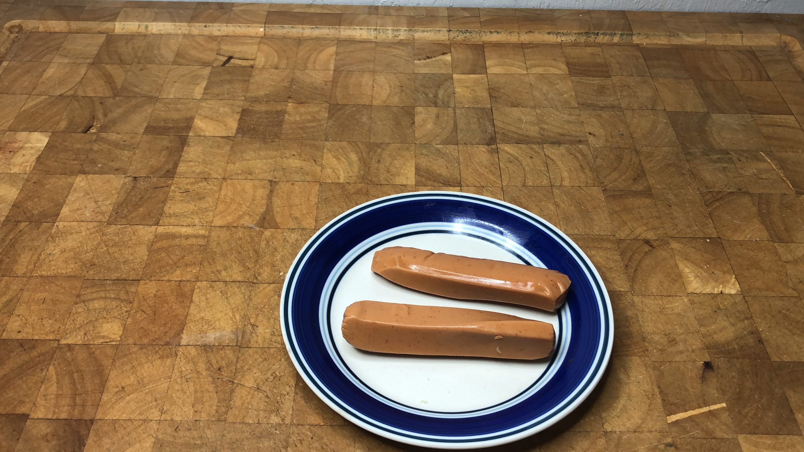 two hot dogs on a plate on a wooden table