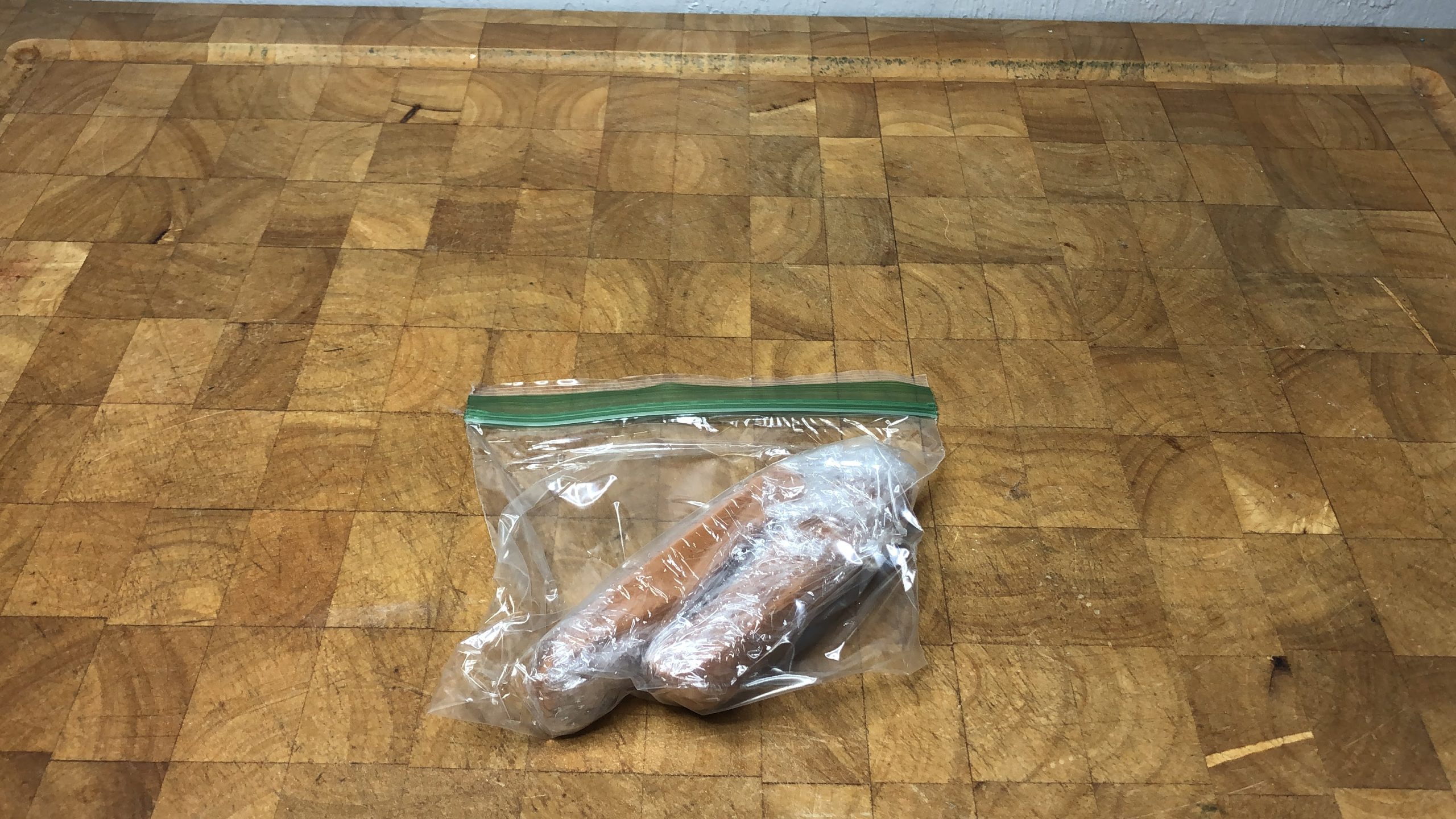 two hot dogs wrapped in plastic wrap sealed in a freezer bag