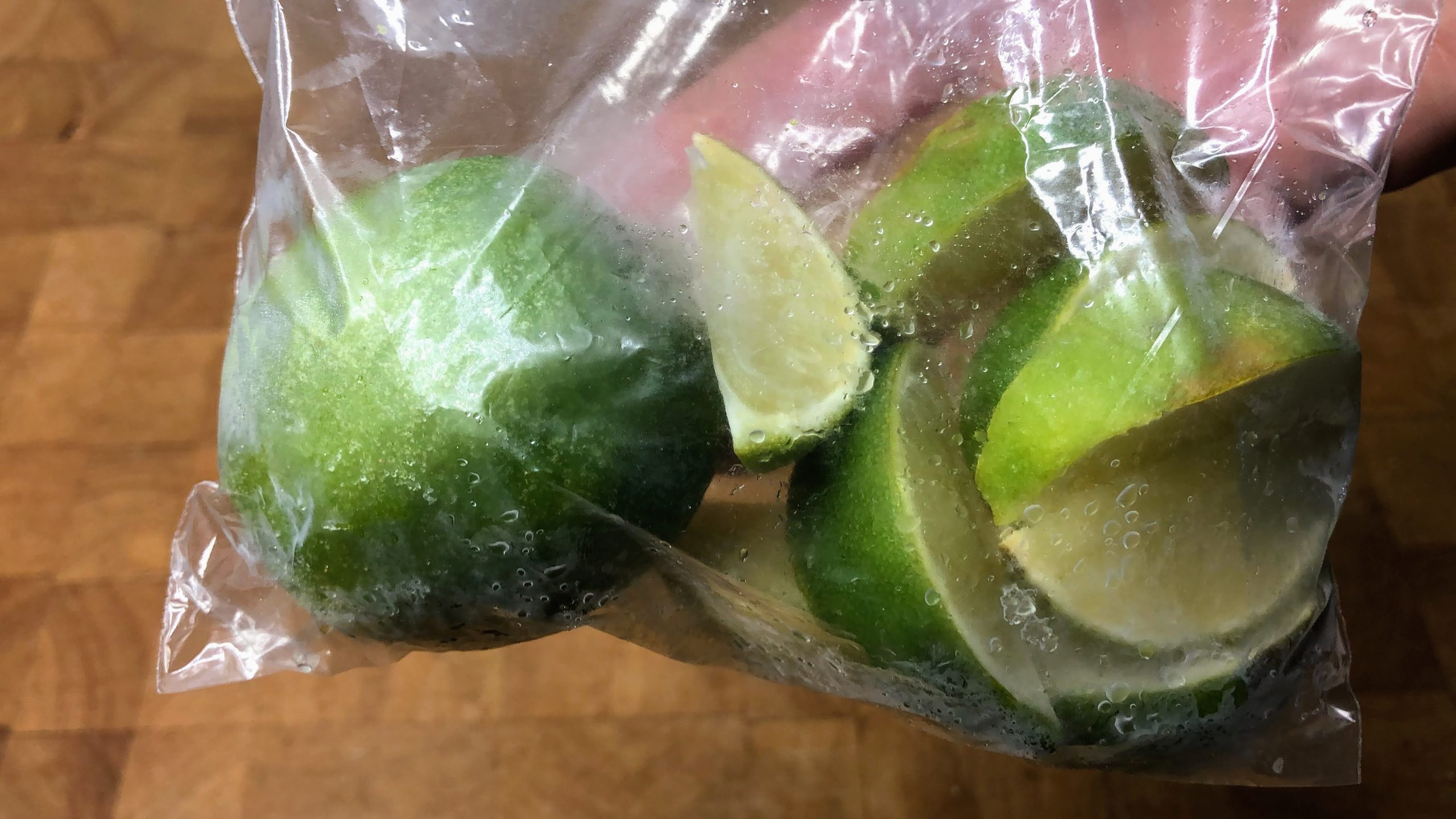 whole and sliced defrosted limes in a freezer bag