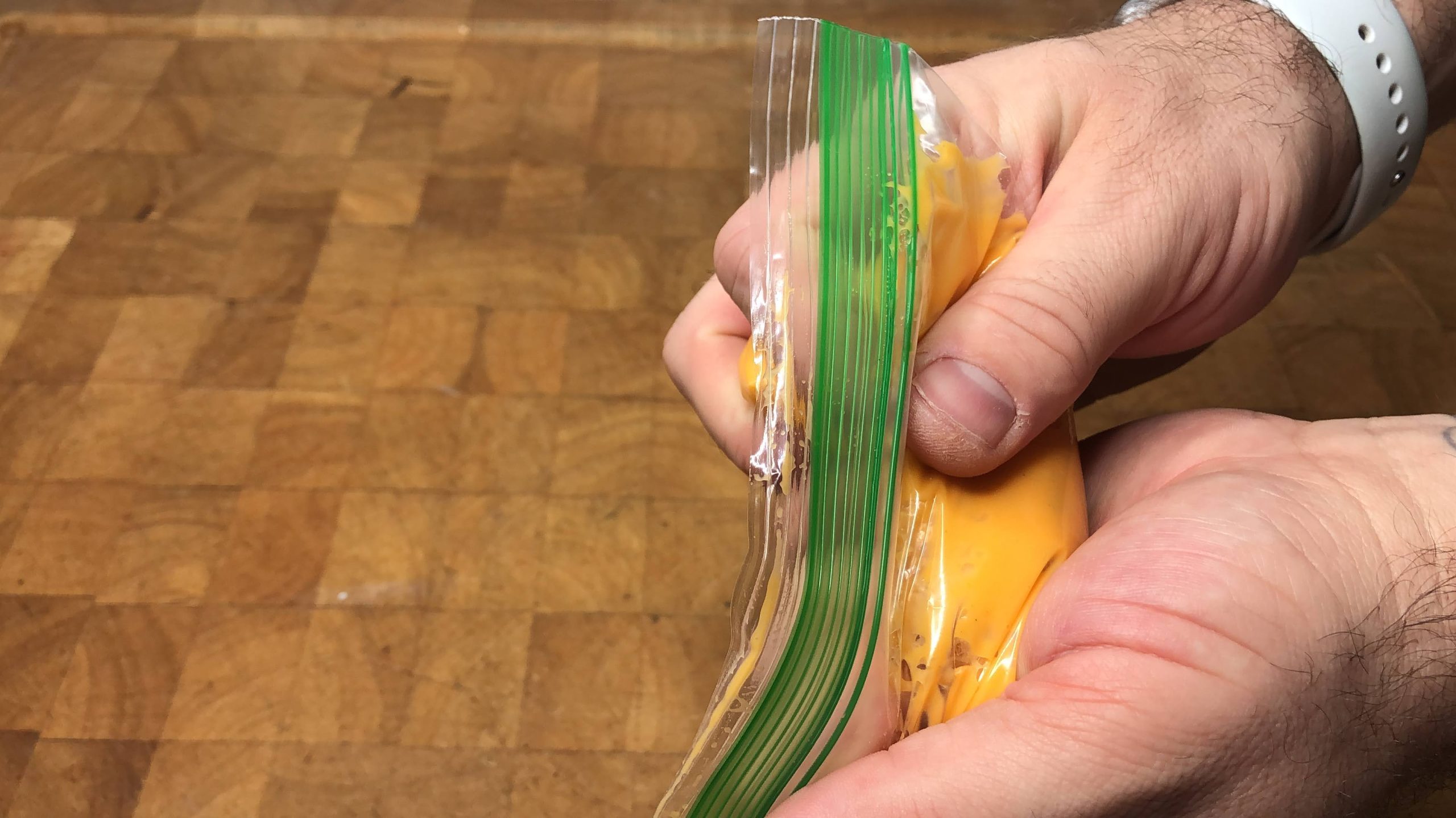 squeezing air out of a freezer bag filled with nacho cheese