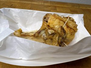 piece of rotisserie chicken in a paper tray