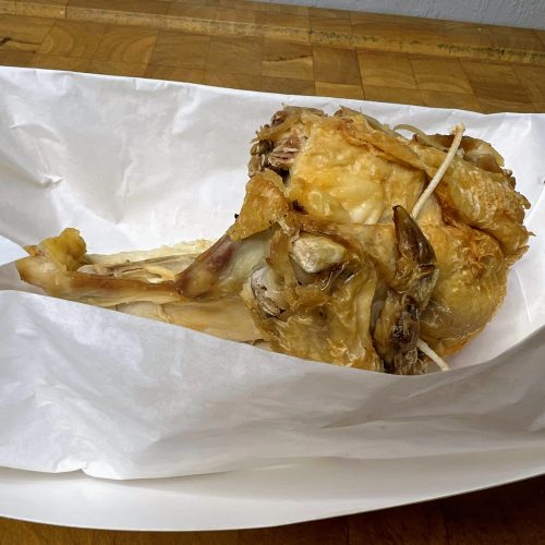 piece of rotisserie chicken in a paper tray
