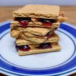 Stack of PB&J graham cracker sandwiches on a plate.