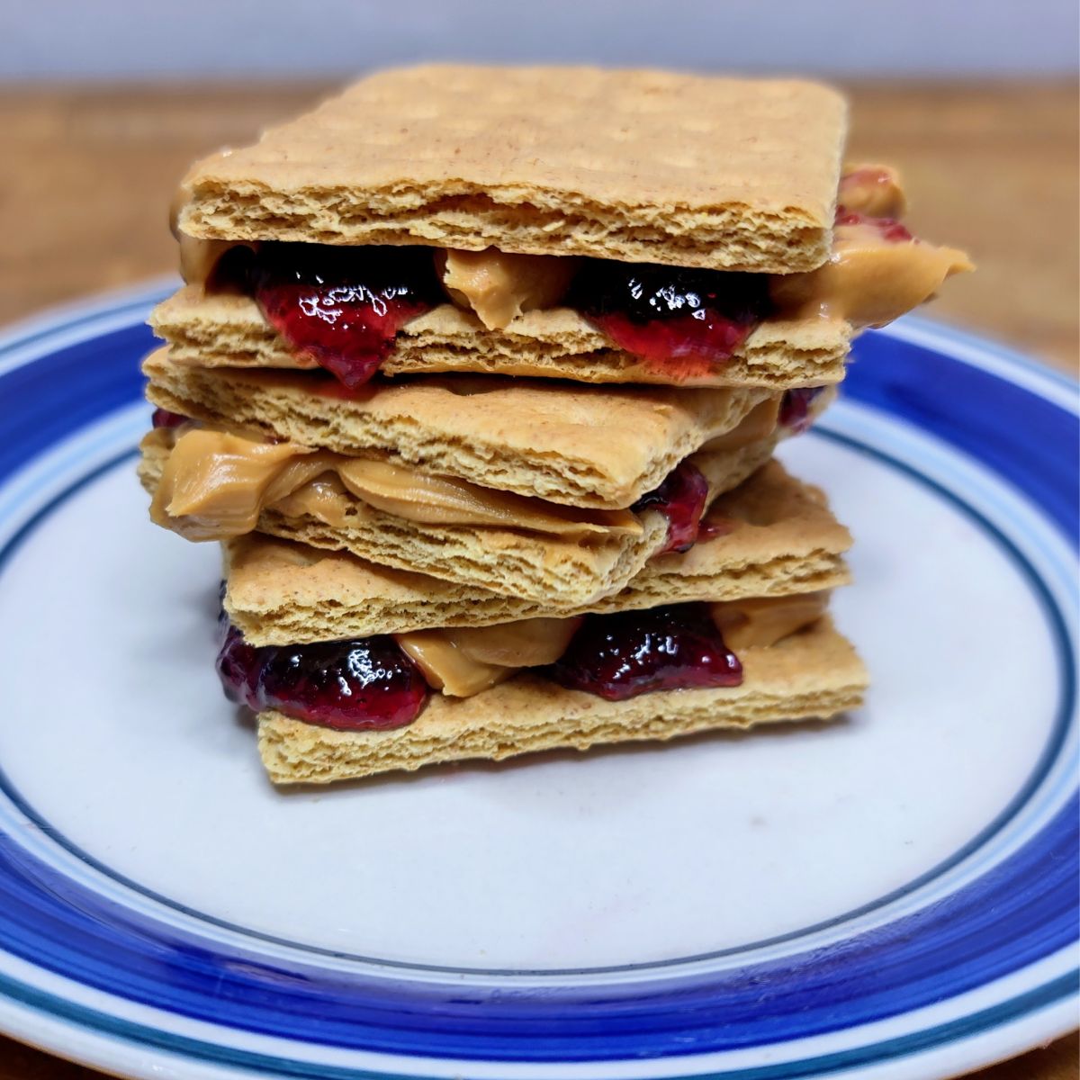 Stack of PB&J graham cracker sandwiches on a plate.