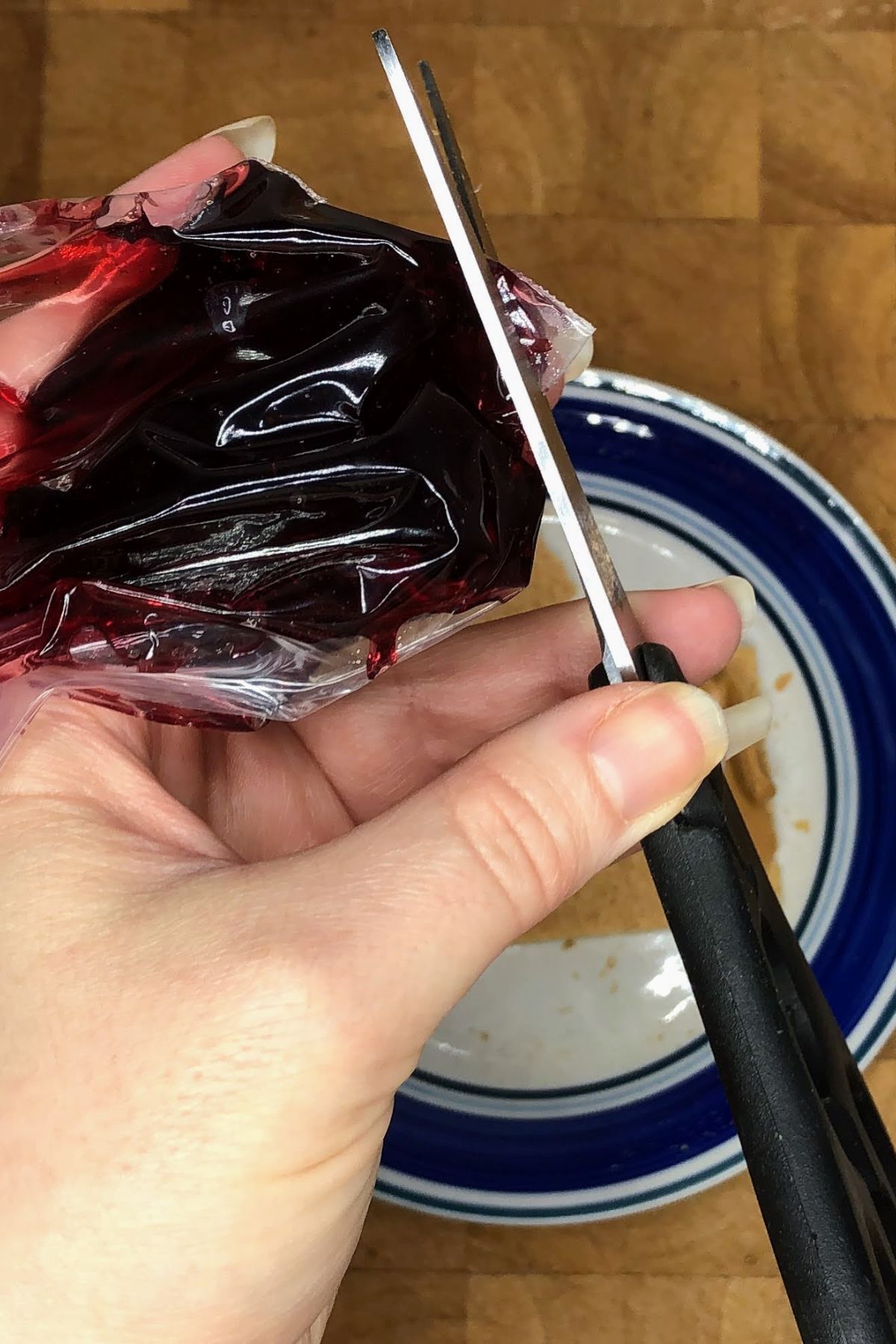 Slicing the tip of a ziplock bag off that is filled with jelly.