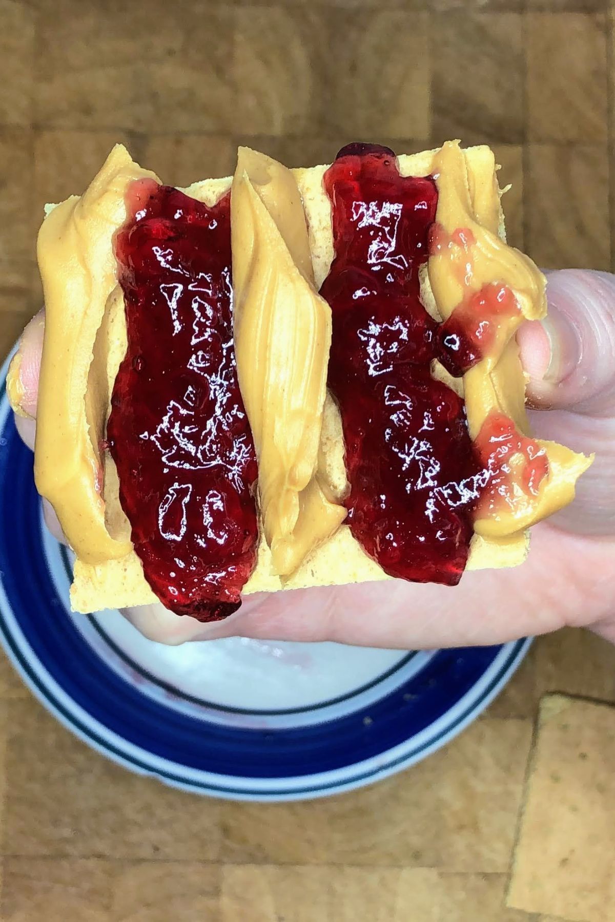 Graham cracker with layers of peanut butter and jelly on it.
