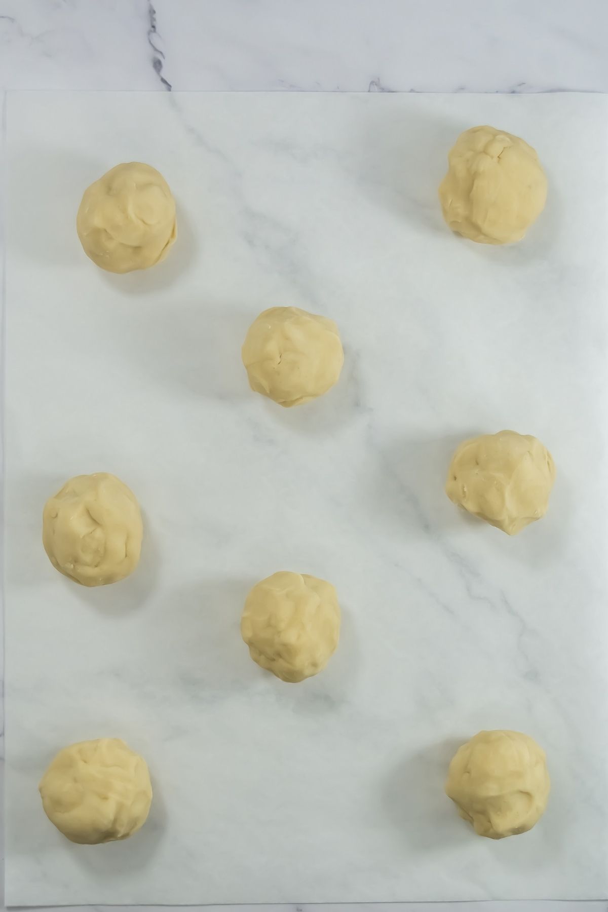 Balls of dough on parchment paper.