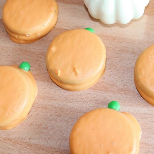 Pumpkin oreos on a wood table.